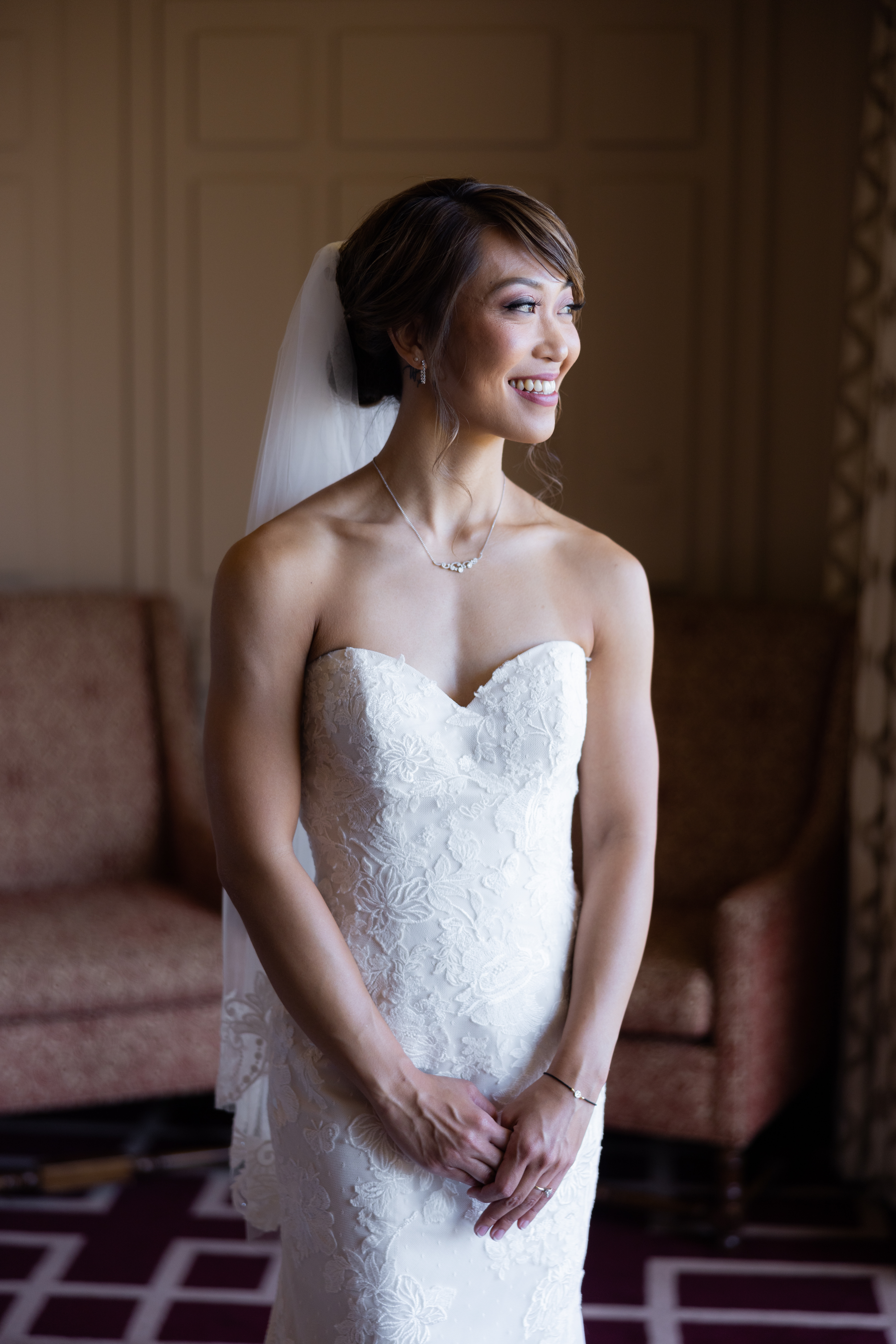 bride in strapless lace wedding dress wearing low chignon bun with finger tip length veil