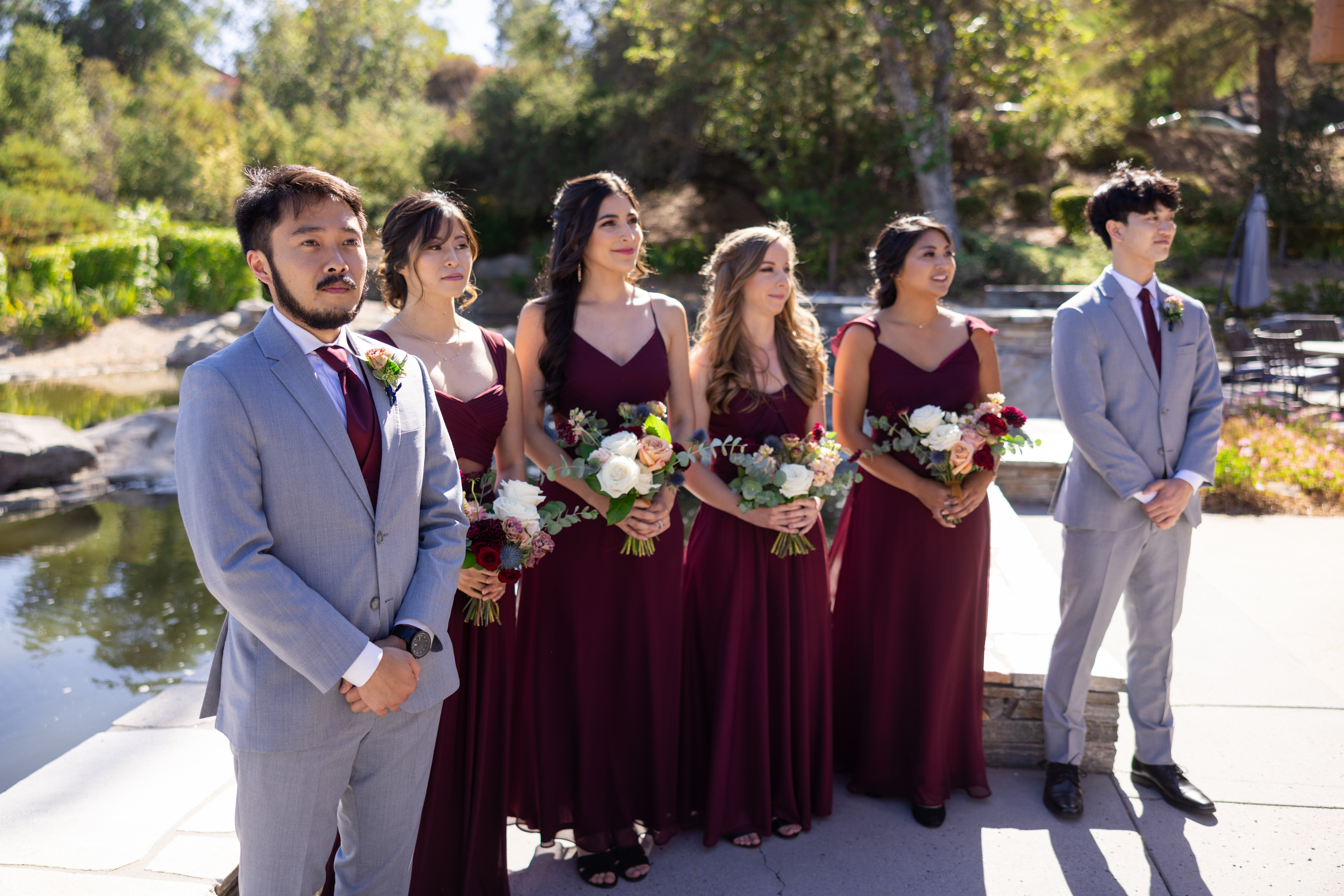 co-ed bridal party in maroon wait during wedding ceremony