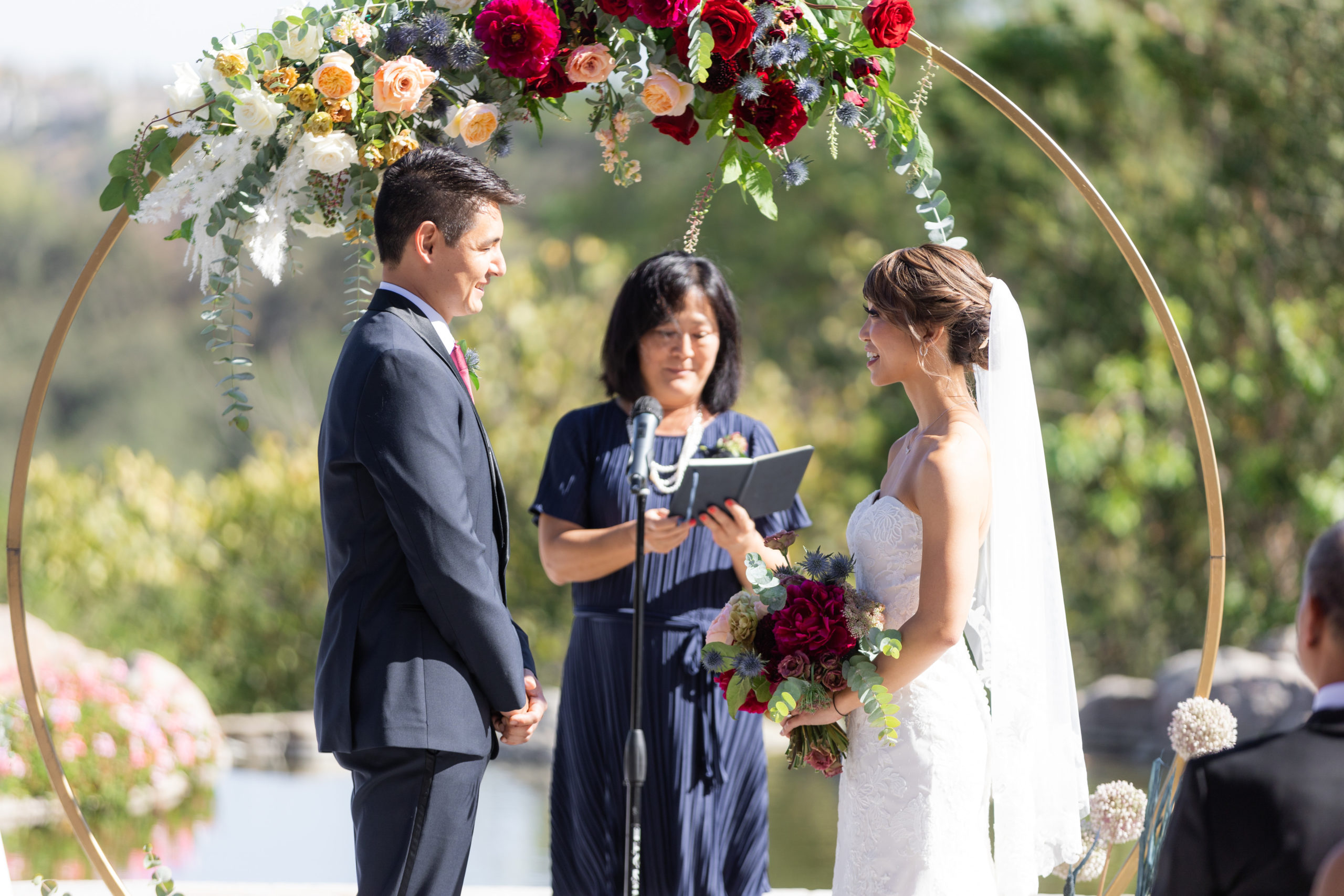 outdoor wedding ceremony at Dove Canyon Gold Club with with gold circle ceremony arch with jewel toned florals