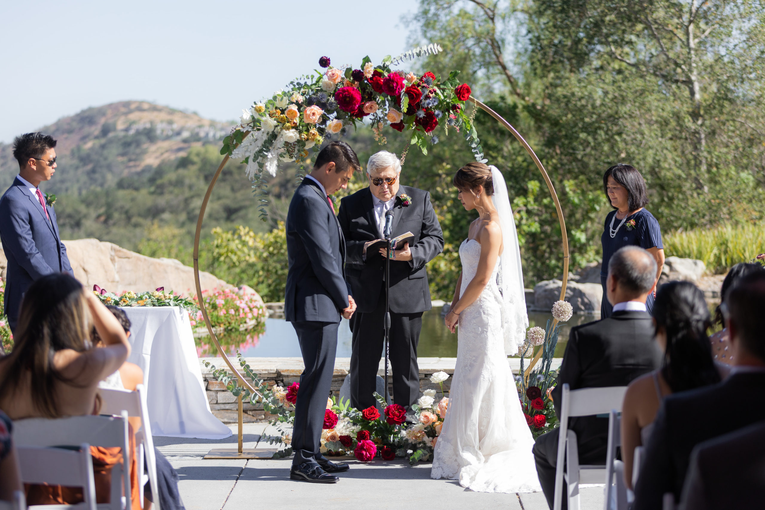 outdoor wedding ceremony at Dove Canyon Gold Club with with gold circle ceremony arch with jewel toned florals