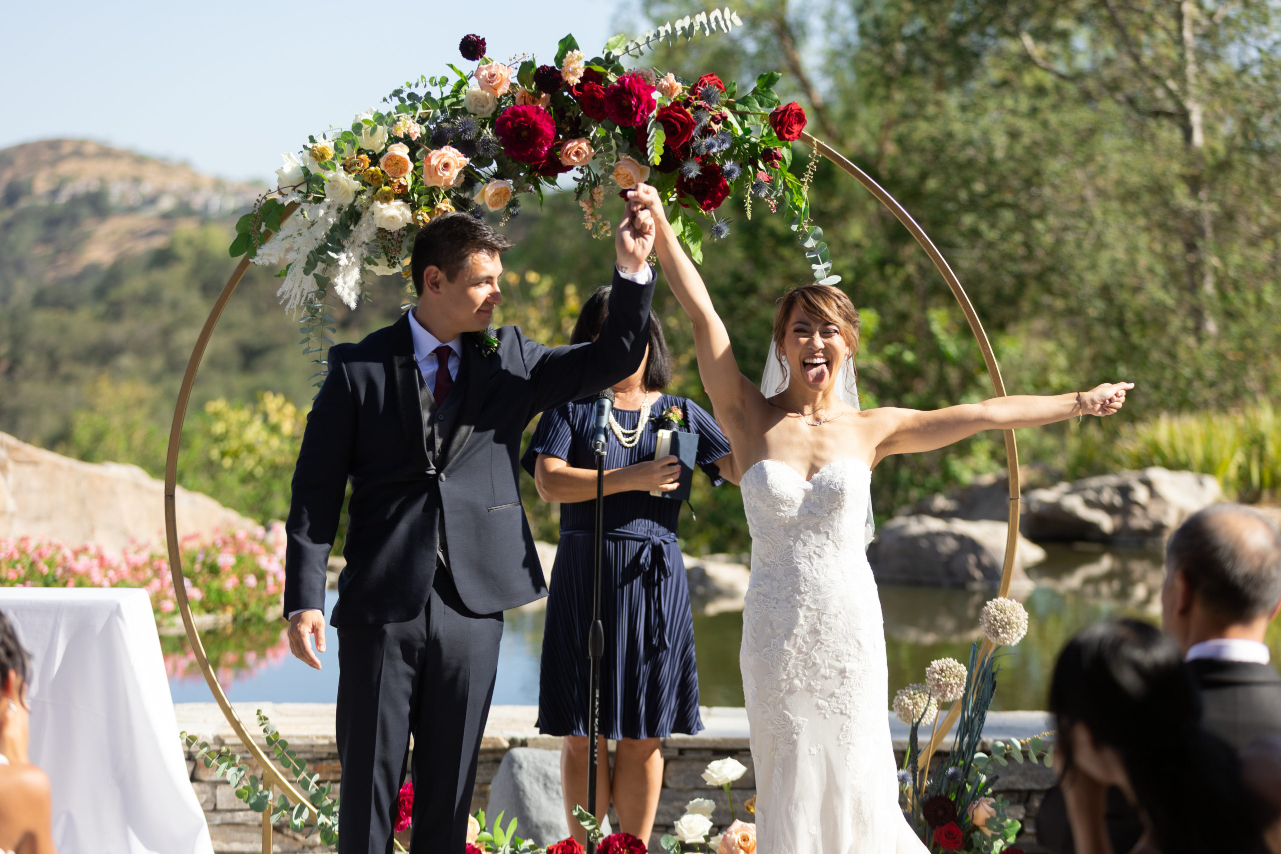 bride and groom recessional during outdoor wedding ceremony at Dove Canyon Gold Club with with gold circle ceremony arch with jewel toned florals