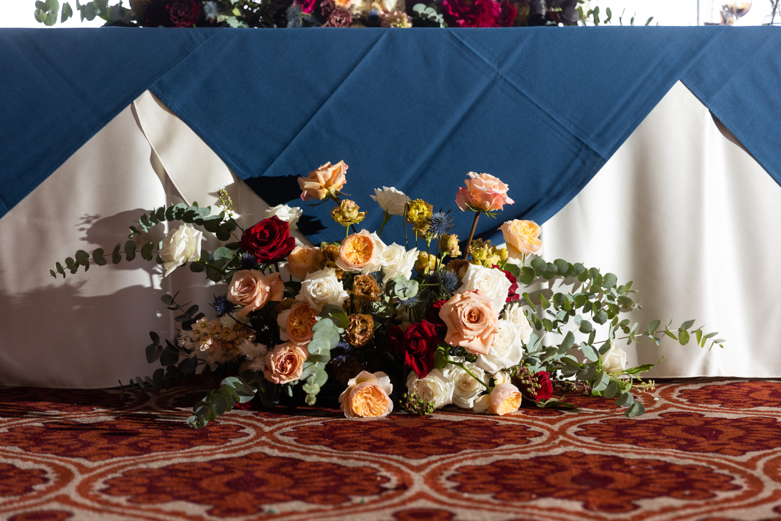 jewel toned indoor wedding reception at Dove Canyon Golf Club with navy linen and maroon napkins 