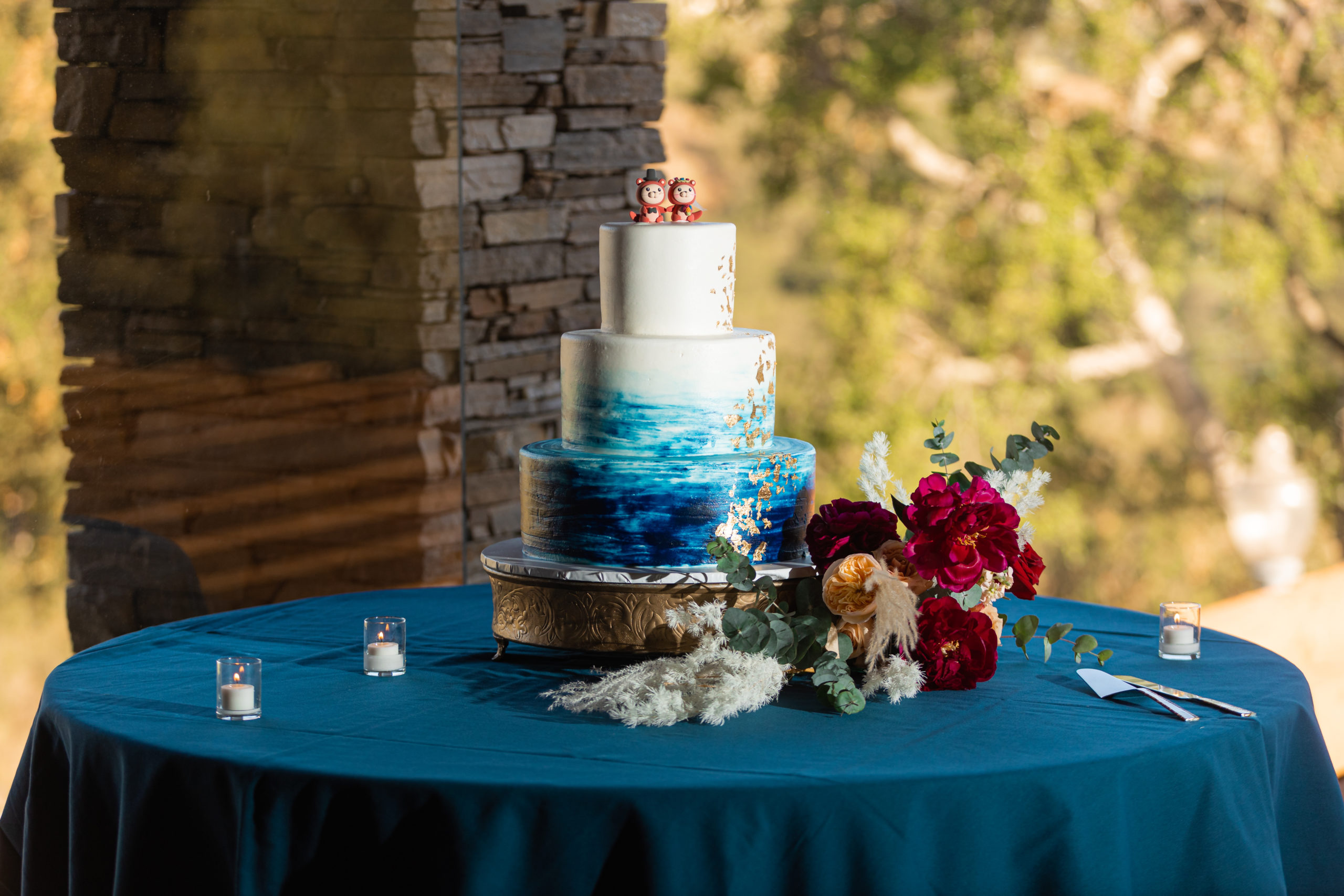 three tier wedding cake with blue water color and otter cake toppers