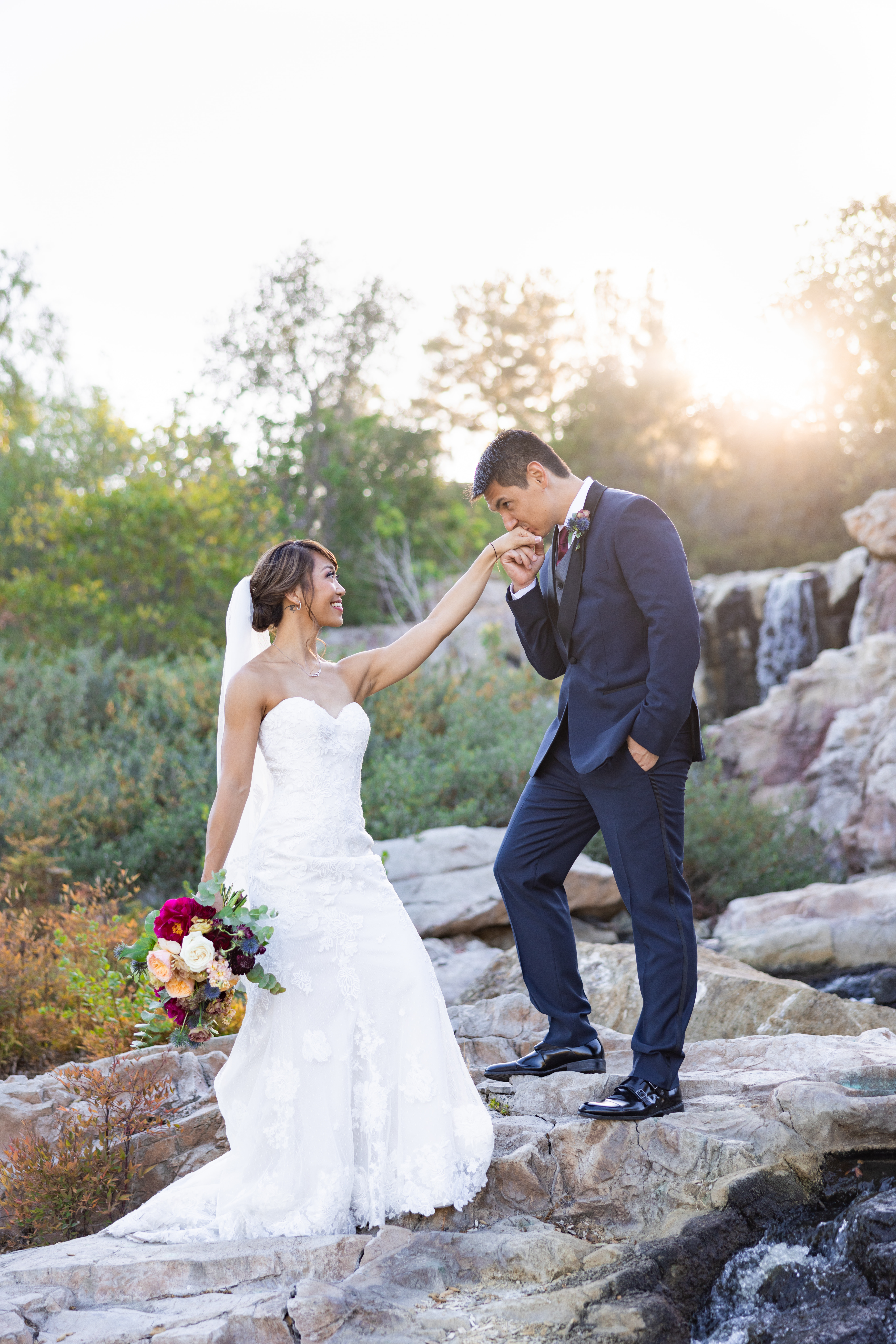 bride in strapless lace wedding dress and groom in navy tuxedo take outdoor sunset portrait photos by waterfall at Dove Canyon Golf Club