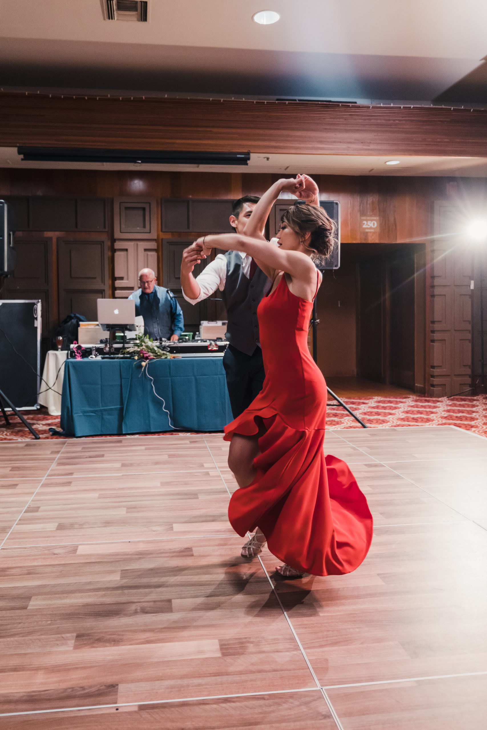 bride in red reception dress and groom have first dance