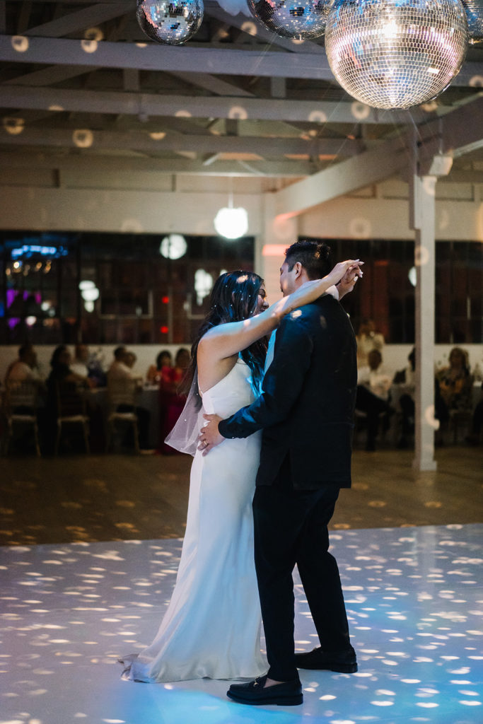 bride and groom first dance under disco ball lighting