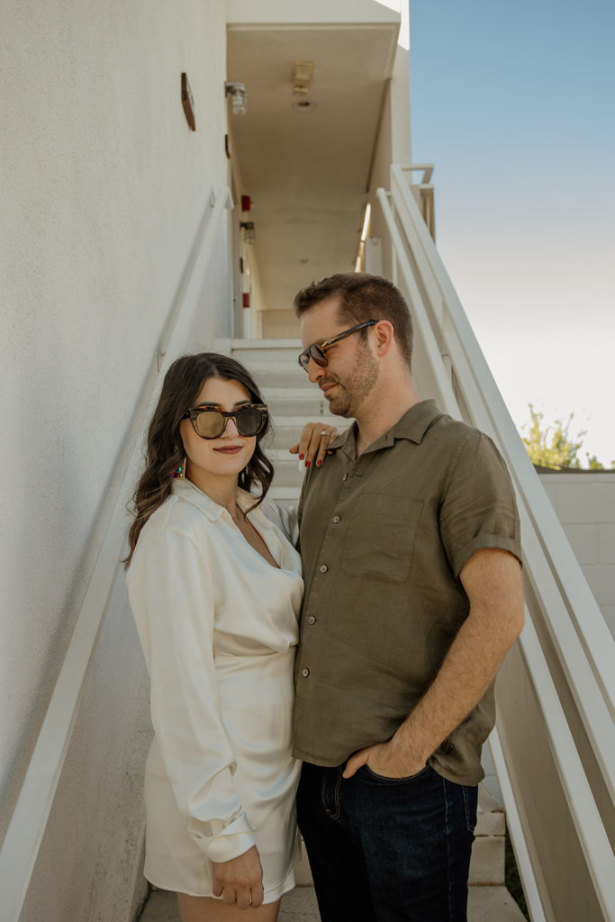 mid-century inspired desert engagement photo session with bride to be in silk mini dress and groom in brown button up on outdoor staircase