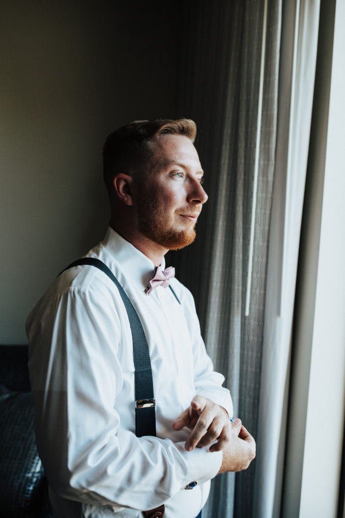 groom in pink bowtie and white shirt with black suspenders