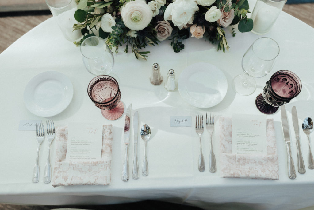 wedding reception sweetheart table with pink patterned napkins and deep pink goblets and white linen