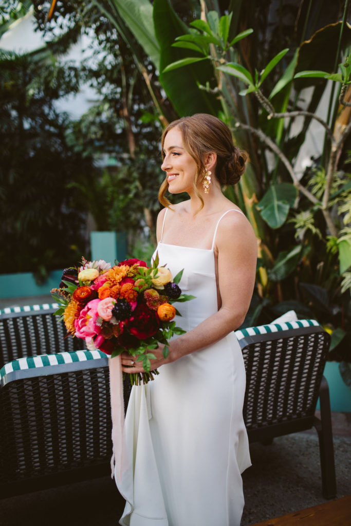 bride in modern square neck spaghetti strap wedding dress with colorful bridal bouquet
