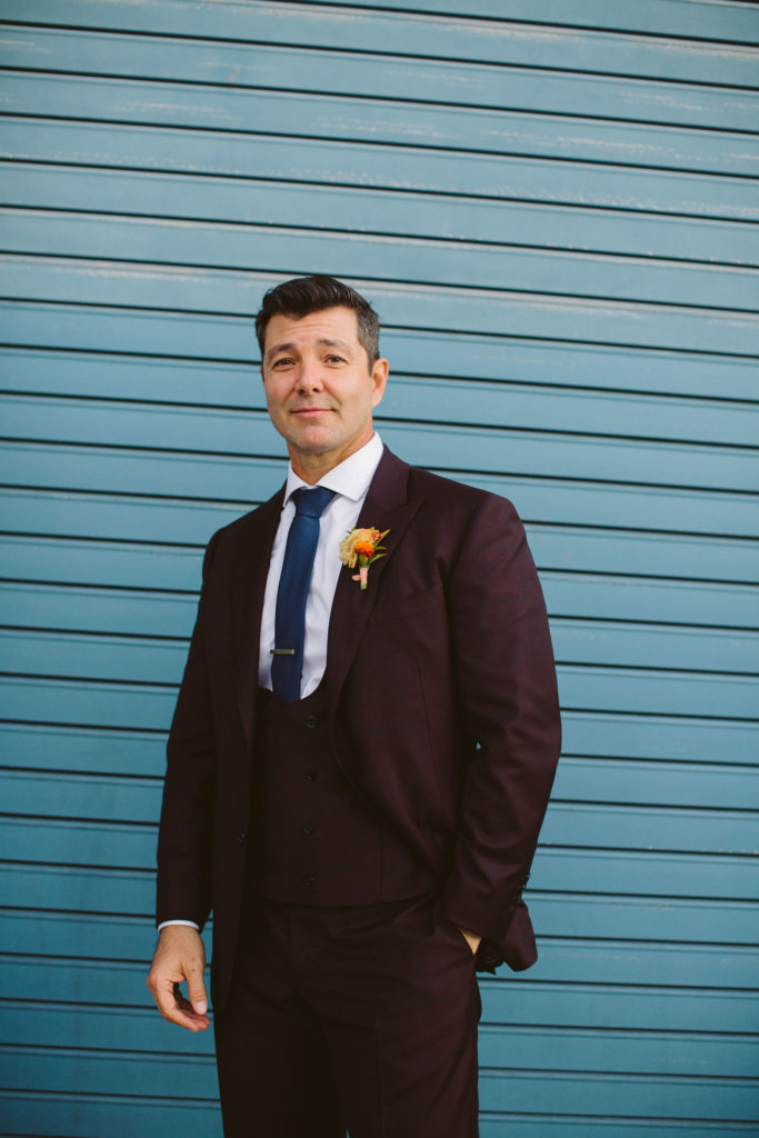 groom in deep plum suit with blue tie