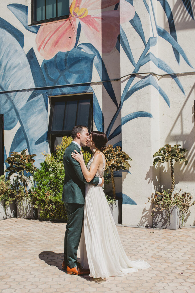 bride in embellished deep v neck wedding dress with a chiffon skirt does first look with groom in custom green suit at Hotel Figueroa