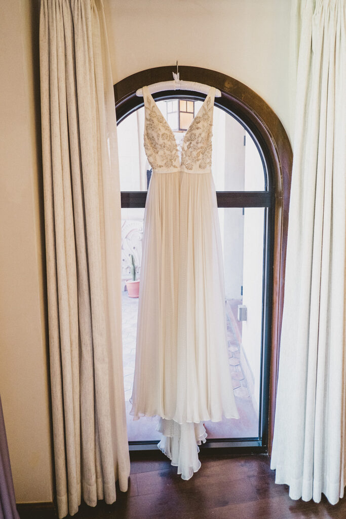 embellished deep v neck chiffon wedding dress hanging from arch doorway