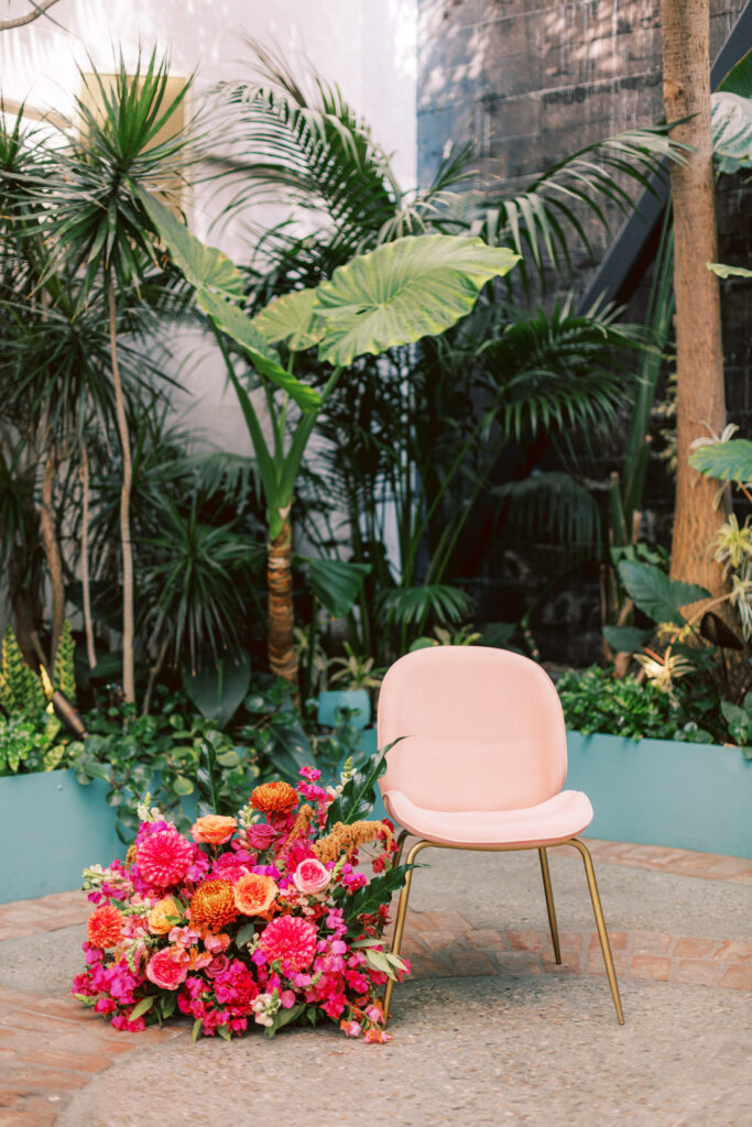 pink chair with gold legs at ceremony with brightly colored floral arrangement for fiesta themed wedding at Grass Room