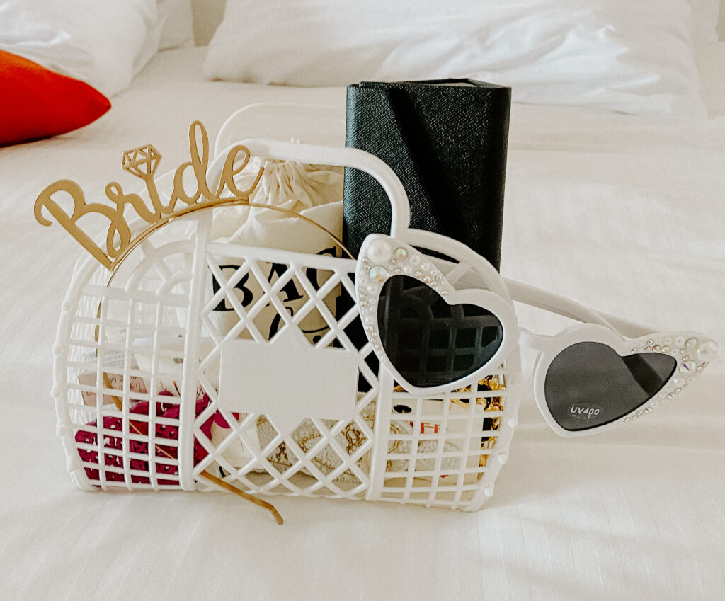 Bachelorette party gift bag with heart shaped pearl and gem embellished sunglasses and gold headband reading bride