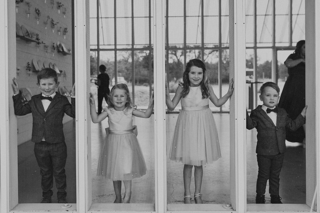 flower children and ring bearers stands in windows of wedding venue