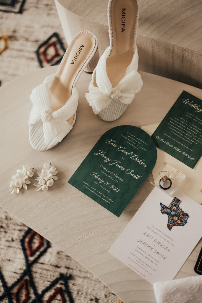 modern bridal detail shot with white bow heeled sandals and green wedding invitation suite 