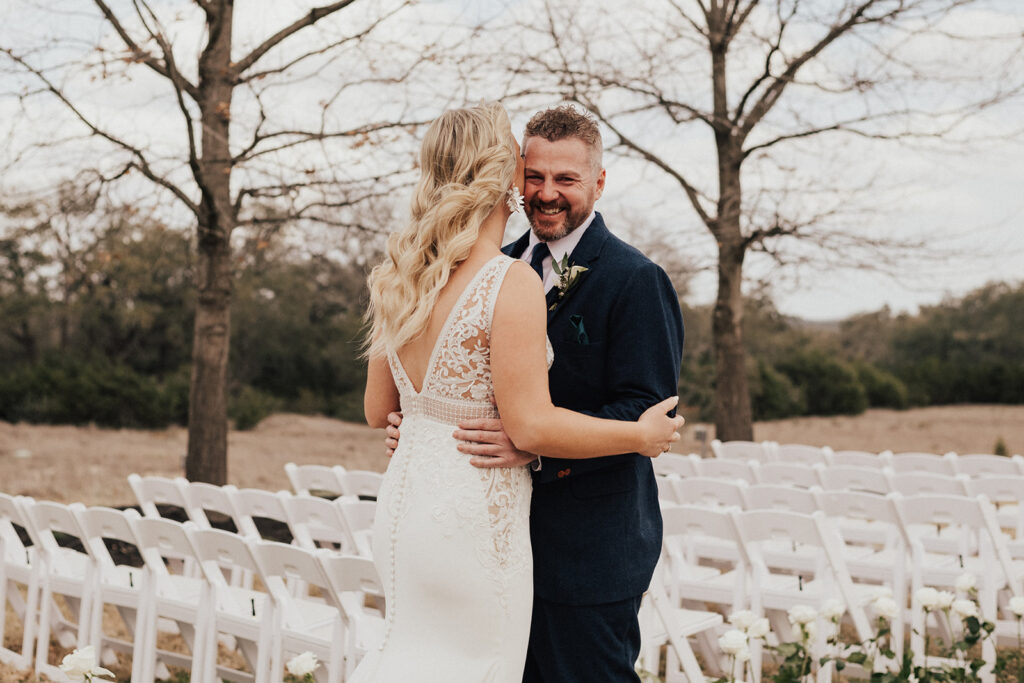 bride in deep v neck wedding dress with lace cut out has first look with groom in navy blue suit before their destination wedding 