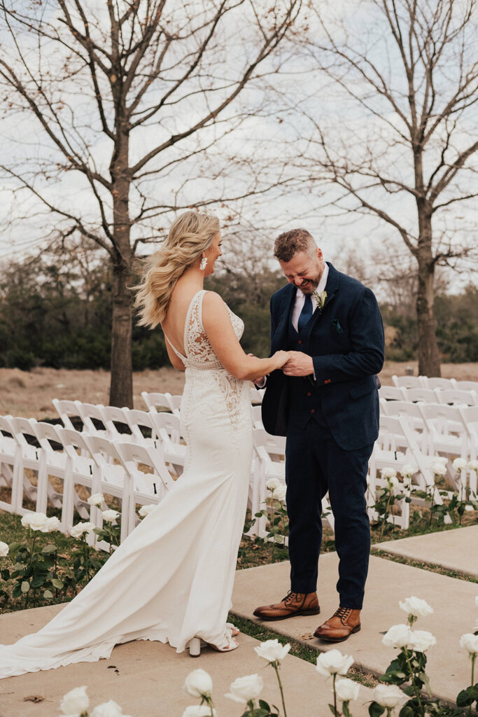 bride in deep v neck wedding dress with lace cut out has first look with groom in navy blue suit before their destination wedding 