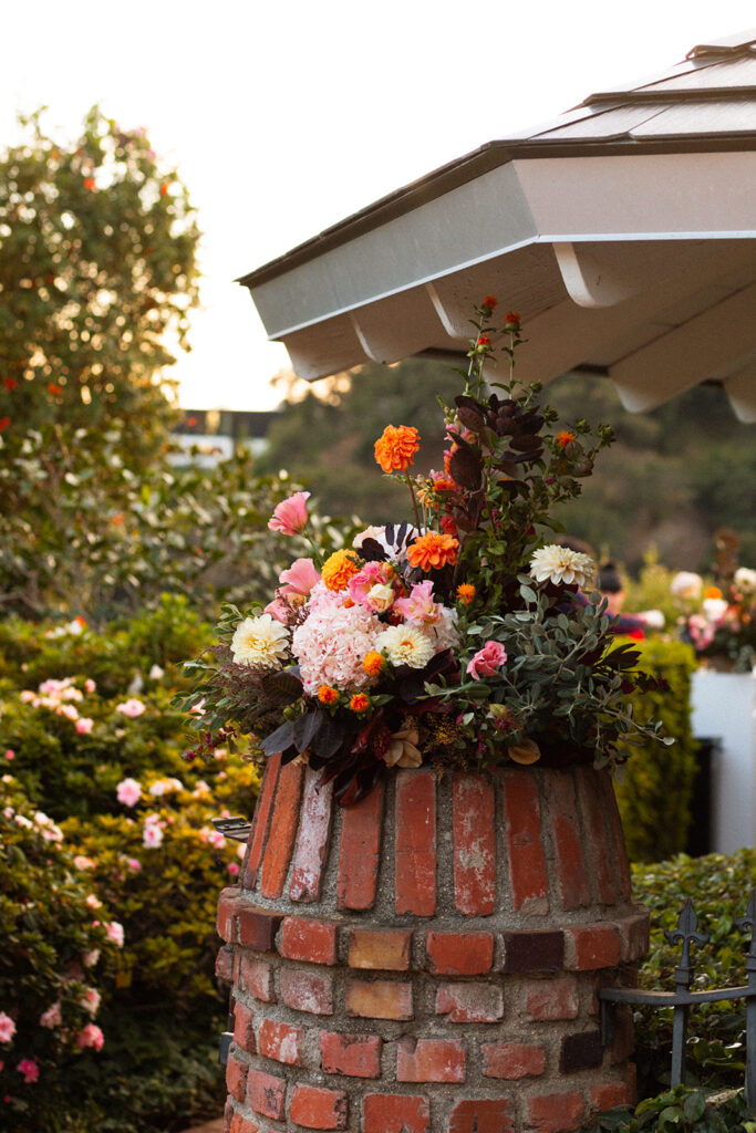 brick gate posts covered in sunset themed floral arrangements