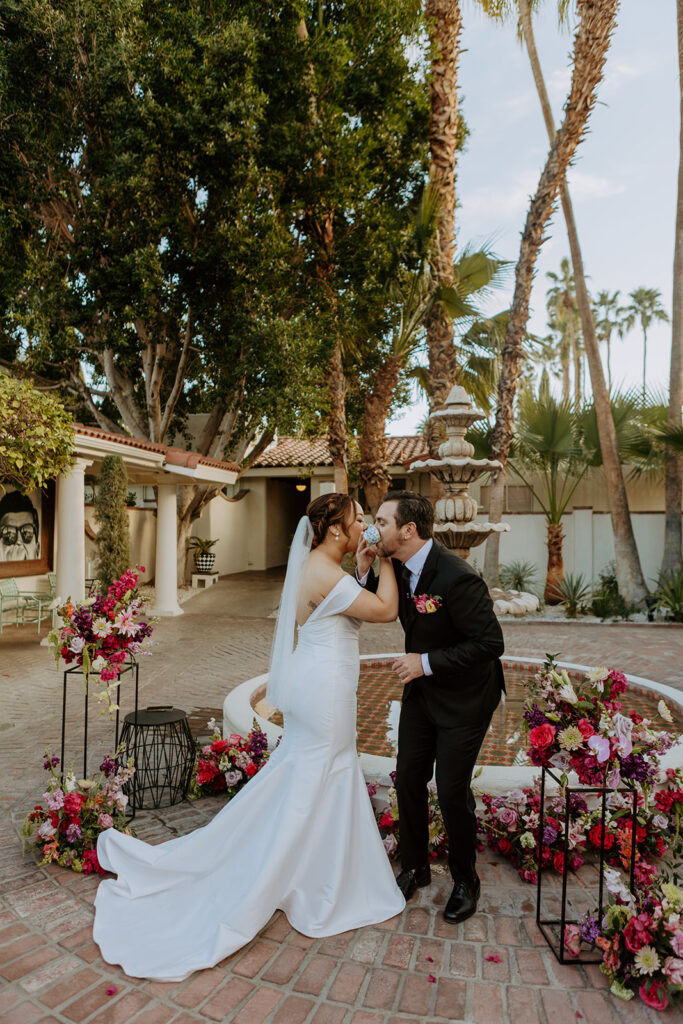 bride and groom perform tea ceremony during colorful wedding ceremony in front of fountain at Villa Royal Palm Springs