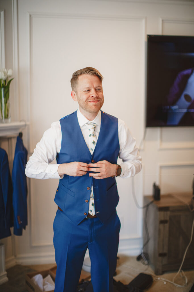 groom getting ready in blue suit with brown shoes