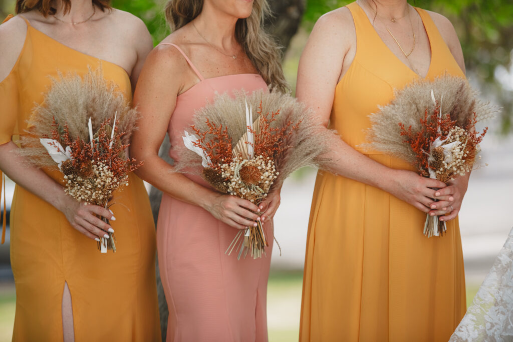 bridesmaids in sunset colored dresses and dried floral bouquets