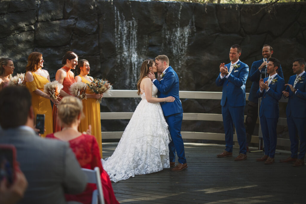 bride and groom first kiss during wedding ceremony at Calamigos Ranch Oak Room