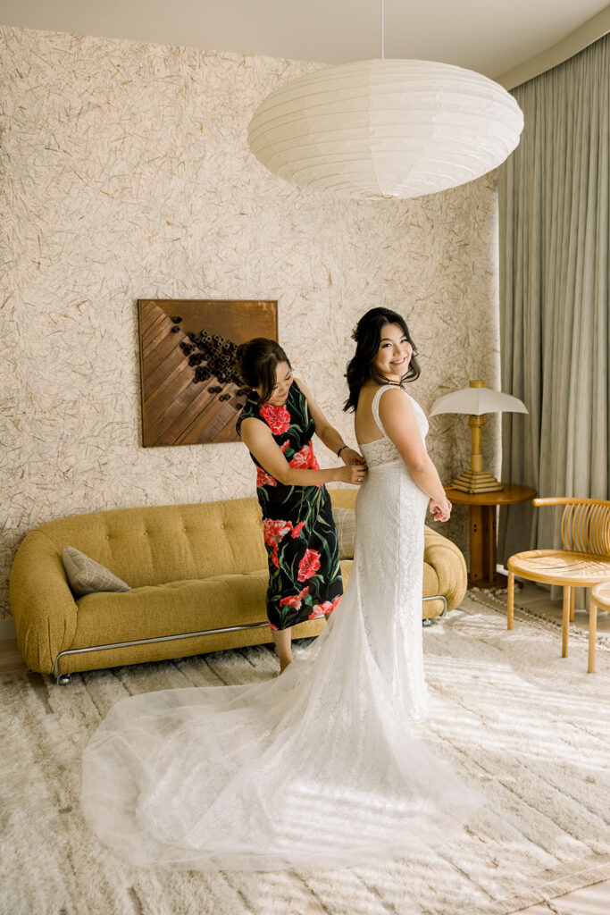 mother of the bride helping bride get into her dress