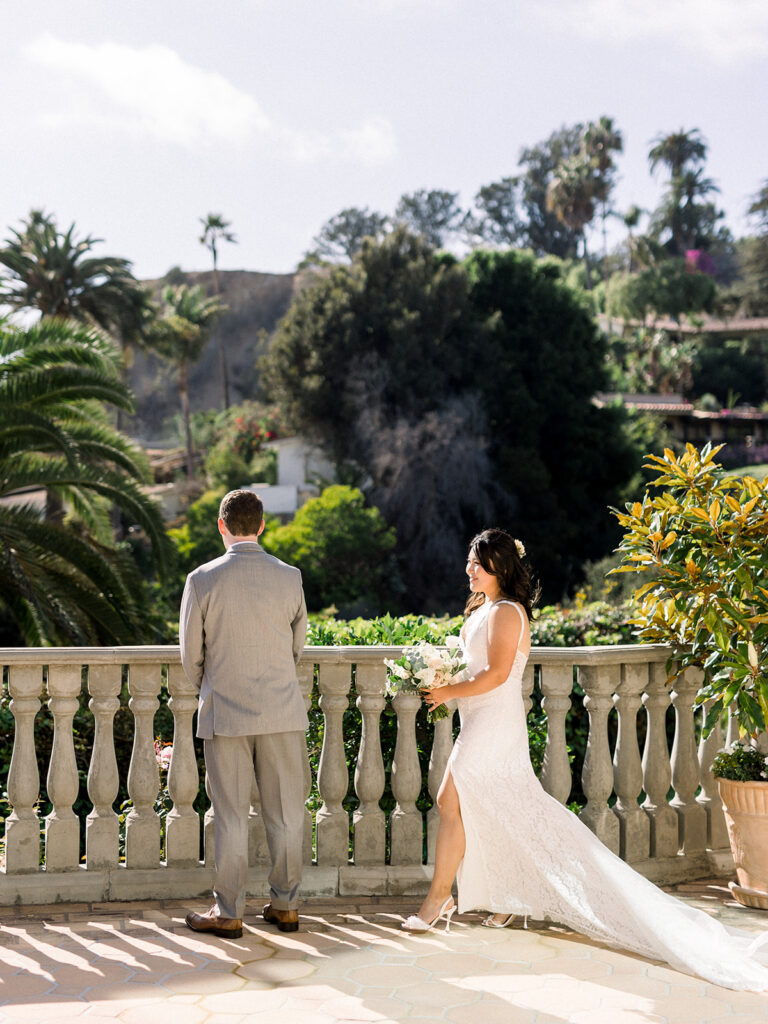 bride in lace dress with long train does first look with grey suit and blue tie at Bel-Air Bay Club