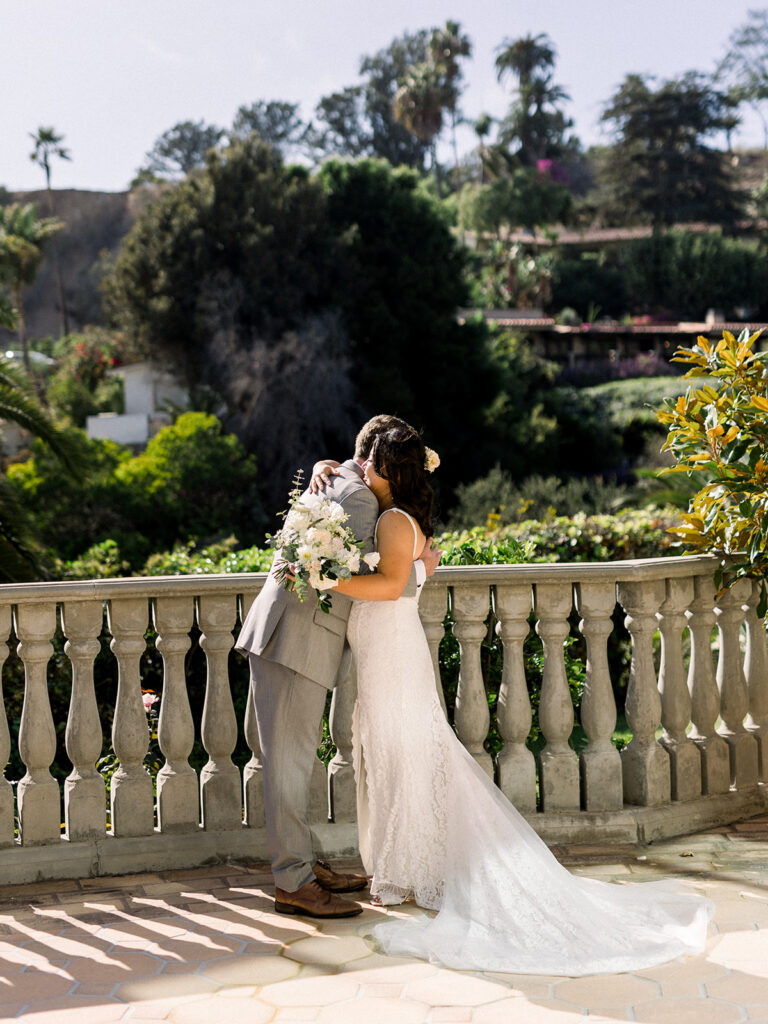 bride in lace dress with long train does first look with grey suit and blue tie at Bel-Air Bay Club
