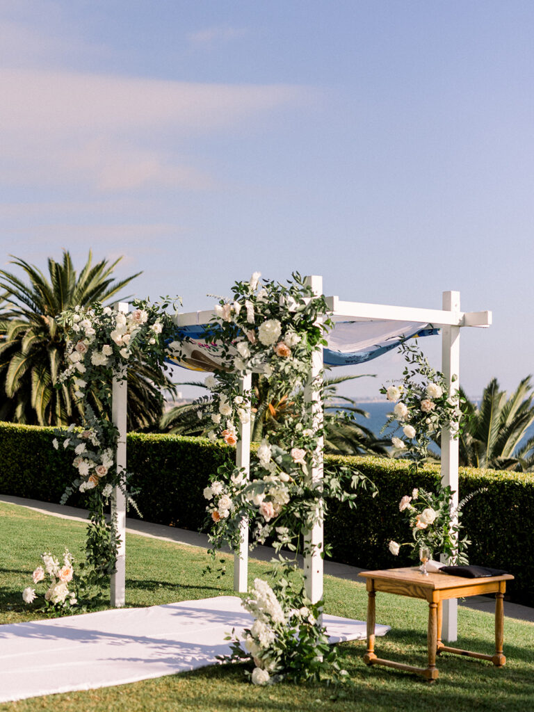 Jewish wedding ceremony chuppah with timeless wedding colors of green, blue and white mixed with soft pink floral arrangements at Bel-Air Bay Club