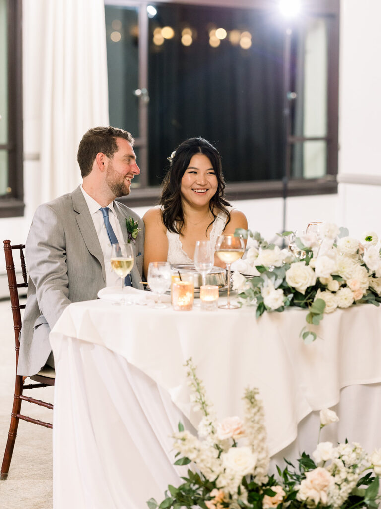 bride and groom sit at sweet heart table during wedding reception at Bel Air Bay Club