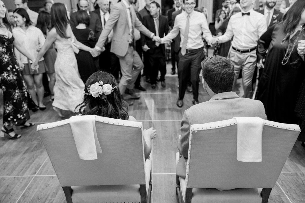 bride and groom sitting in chairs for the horah dance during their wedding reception at Bel Air Bay Club