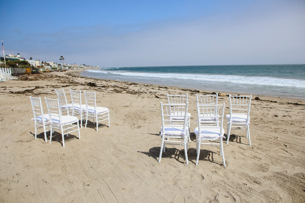 white chairs on sand for private beach wedding ceremony