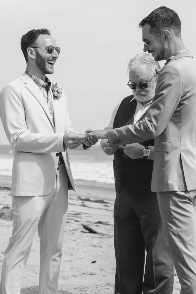 grooms exchanging rings during private beach wedding ceremony