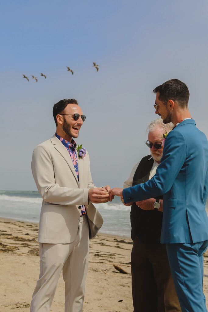 grooms exchanging rings during private beach wedding ceremony
