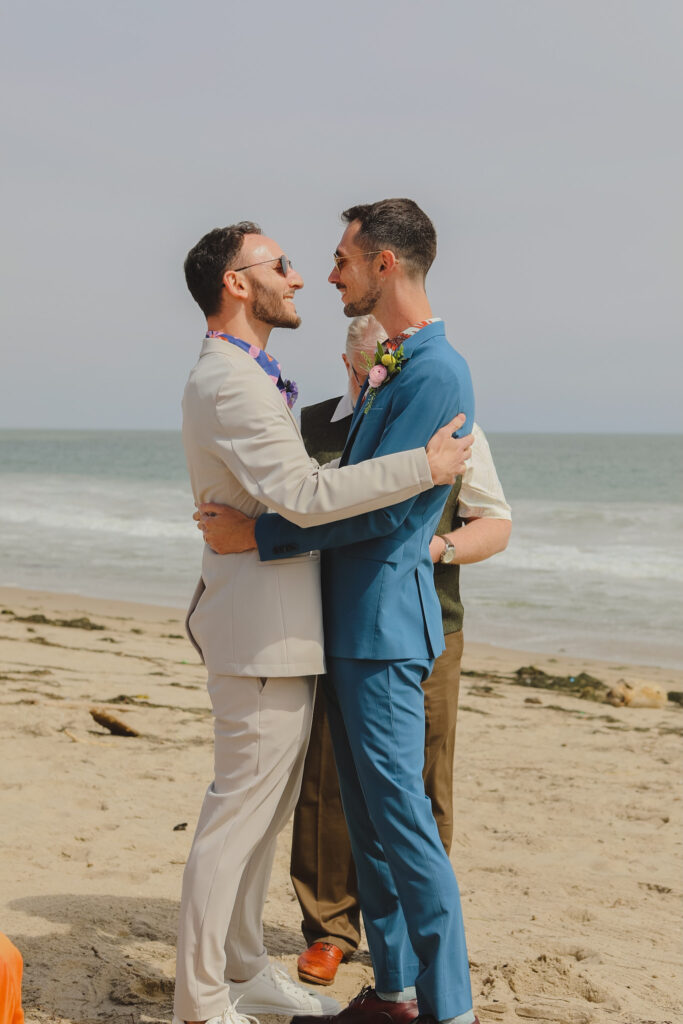grooms share first kiss during private beach wedding ceremony