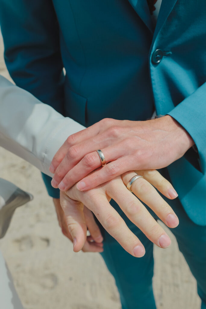 silver wedding rings on grooms' hands