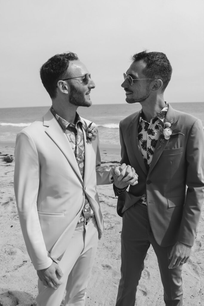 two grooms hold hands in black and white photo