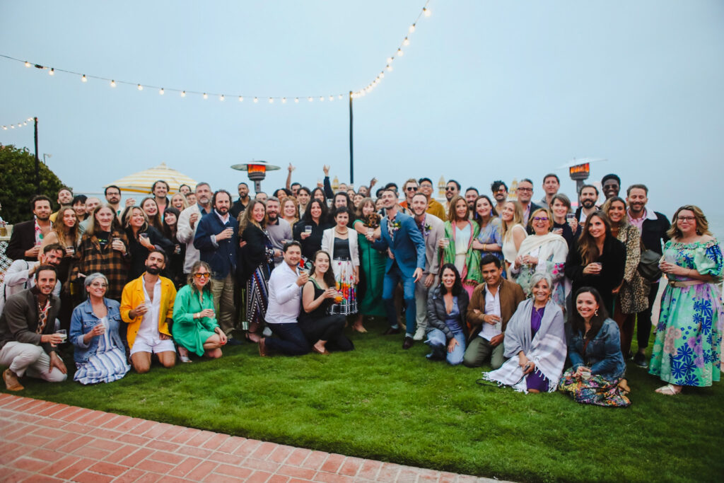grooms take photo with all the guests at their outdoor private beach house wedding