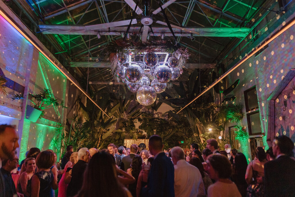 guests dance during wedding reception under disco balls 