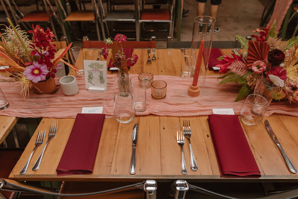 wedding reception at Valentine with pink tropical themed floral arrangements using a mix of dried and real flowers and pink table runner