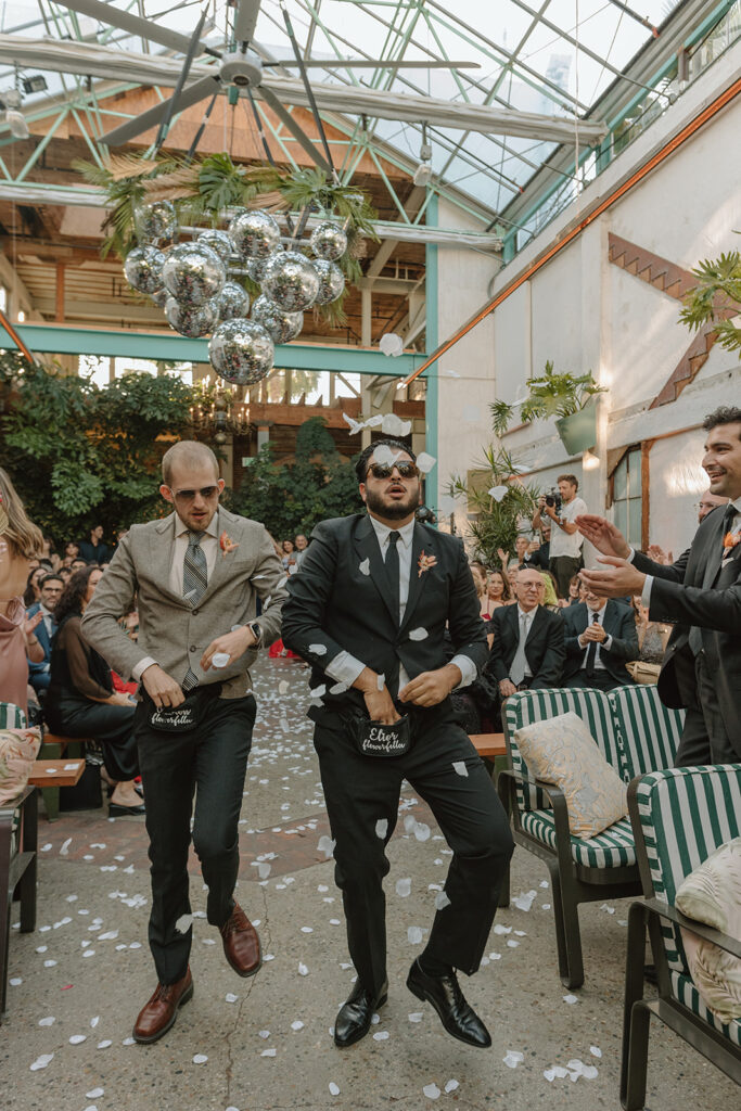 flower men dance down ceremony aisle with fanny packs full of petals