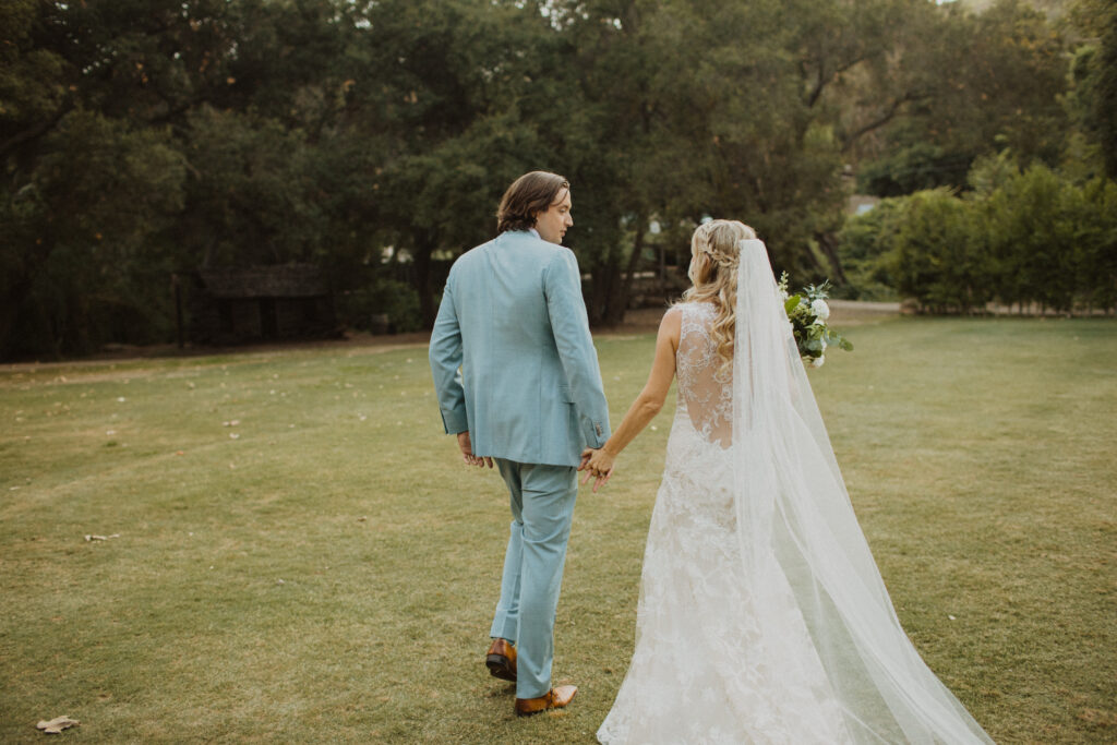 groom in light blue suit with bride in lace wedding dress and cathedral veil