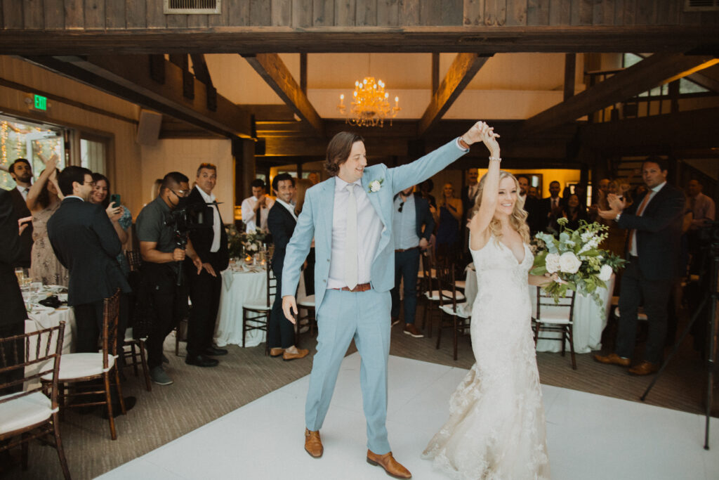 groom in light blue suit and bride in lace wedding dress first dance at wedding reception in the Oak Room at Calamigos Ranch