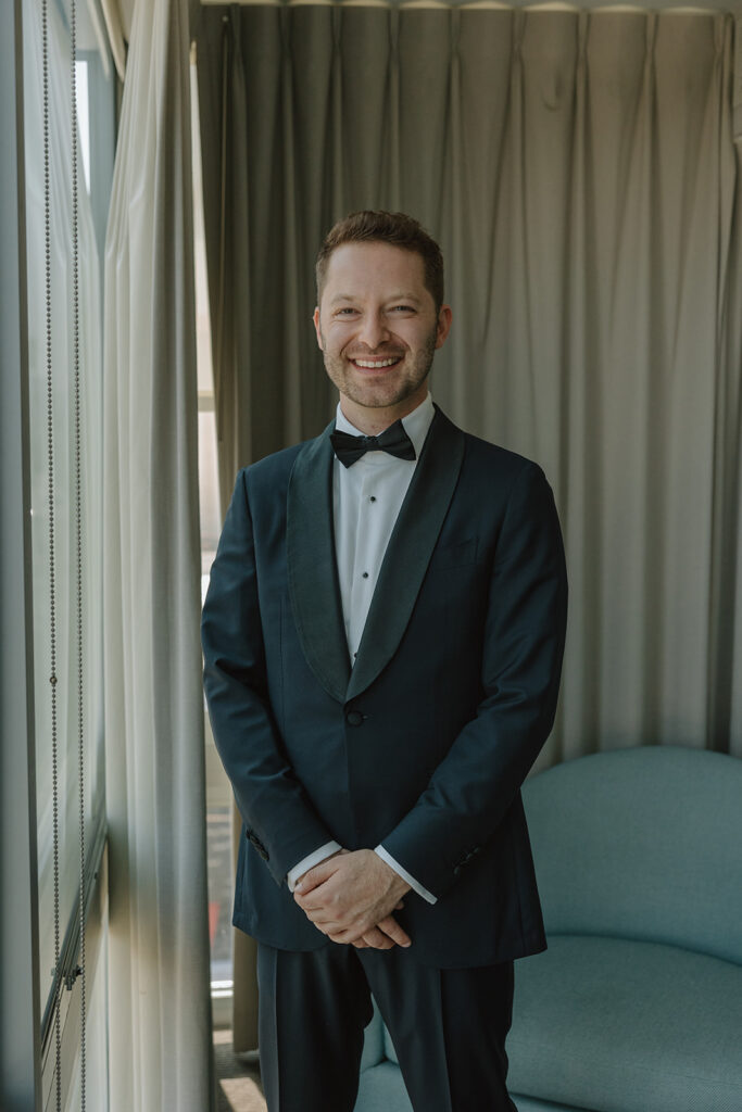 groom in black tuxedo with black bowtie getting ready for wedding