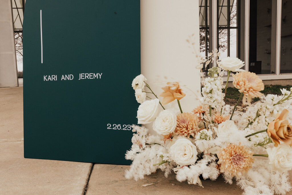 white floral arrangement next to dark green welcome sign