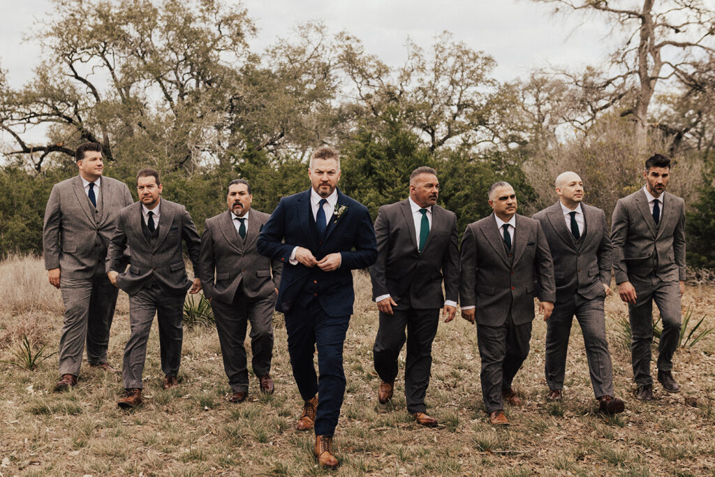 groom in navy blue suit with pocket watch stands with groomsmen in dark navy suits