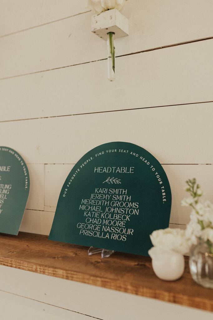 seating chart installation with florals, greenery and forest green geometric shapes